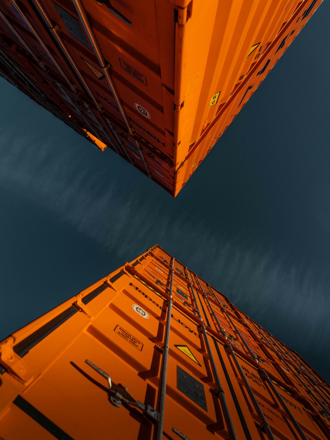 Stacked shipping containers photographed from below against a dark sky.