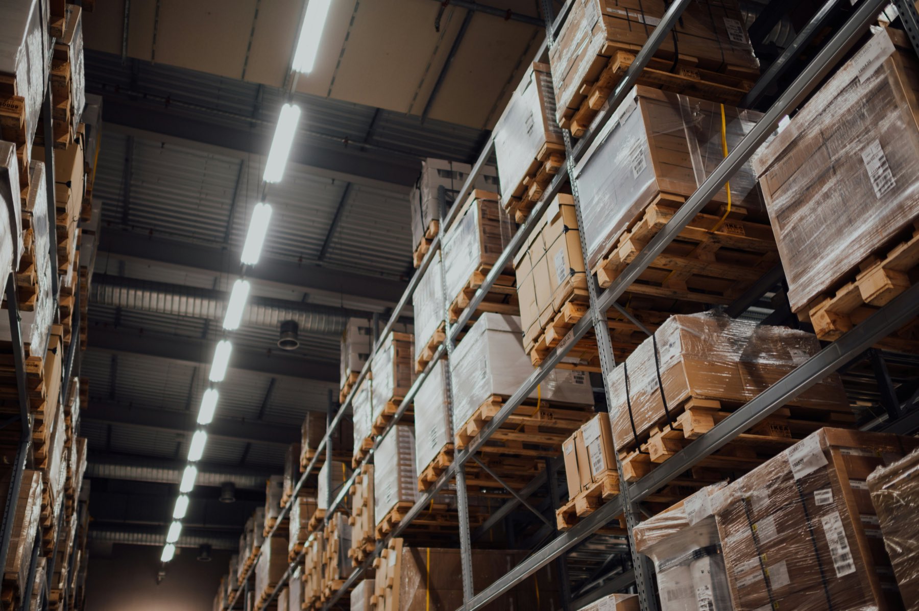 High-bay warehouse racking stacked with palletised freight under overhead lighting.